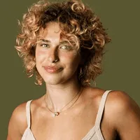 A young woman smiling with a curly hair.